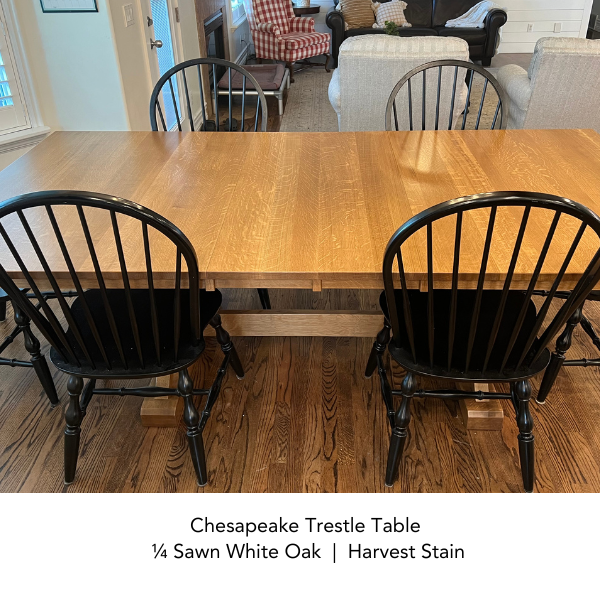 Wooden dining table with black chairs in a room setting.