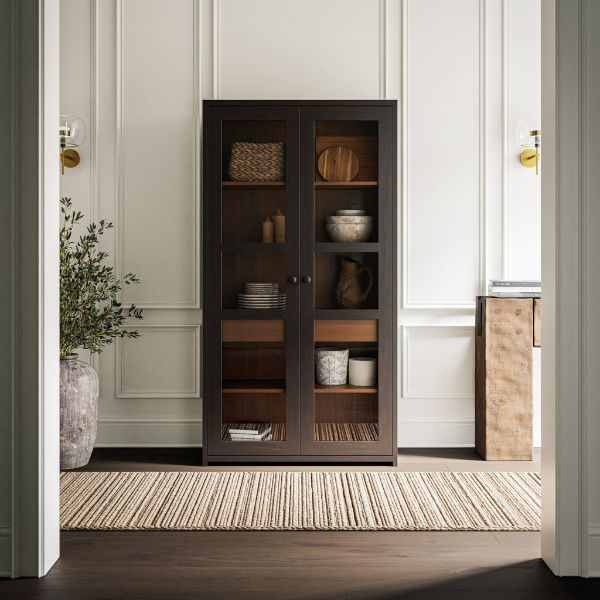 Dark wooden cabinet with glass doors in a room with white walls and a rug.