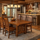 Wooden dining table with chairs in a rustic kitchen setting, featuring the Amish Tables logo.