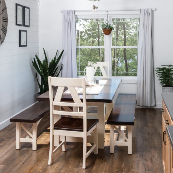 Dining area with a wooden table, chairs, and bench in a bright room with large windows.