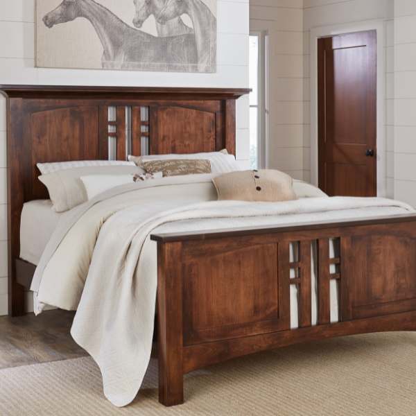 A wooden bed frame with a headboard and footboard, made from brown maple wood, with a cal king size mattress and bedding.