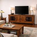 Wooden TV stand with a television, lamps, and a coffee table in a living room.