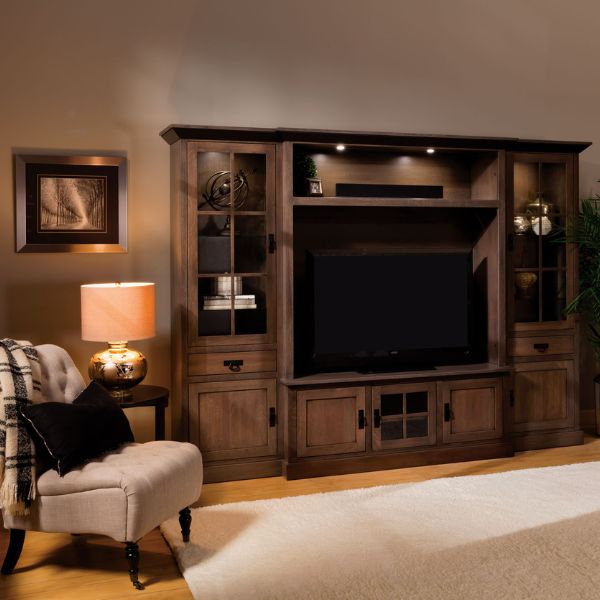 wooden wall unit that has a tv and furniture around it 