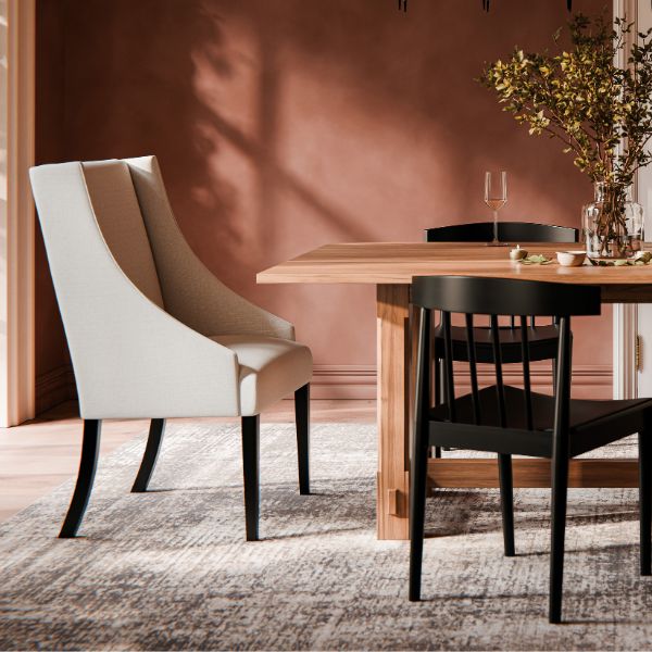 big white chair with 2 black chairs and a wooden table.
