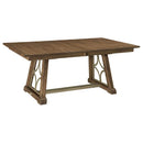 A rectangular trestle table with a brown maple top and a decorative metal base in a gold color.