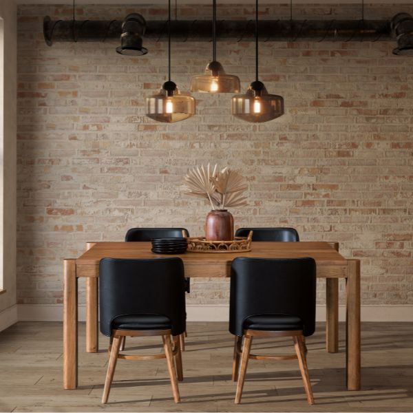 Dining area with wooden table and black chairs against a brick wall.