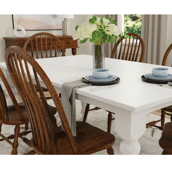 Dining room with a white table and wooden chairs, set for a meal.