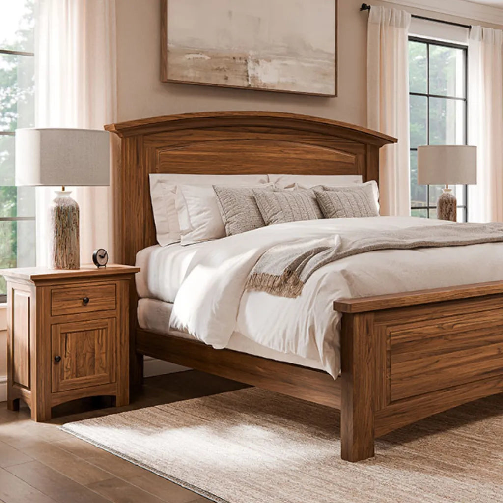 A warm medium-brown wooden bed frame with a curved headboard and matching footboard, styled with white and beige bedding in a bright, modern bedroom.