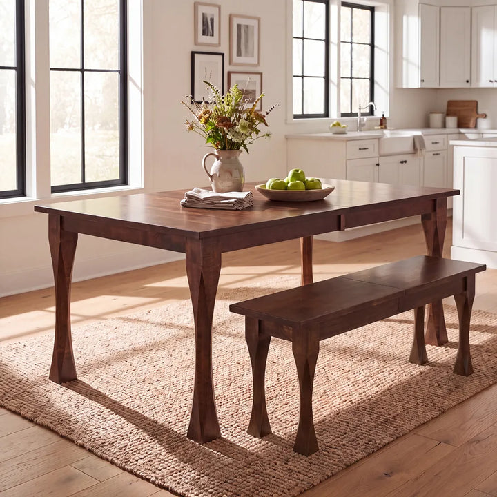 A dark brown maple wooden dining table with matching bench in a bright, modern kitchen setting with natural light.