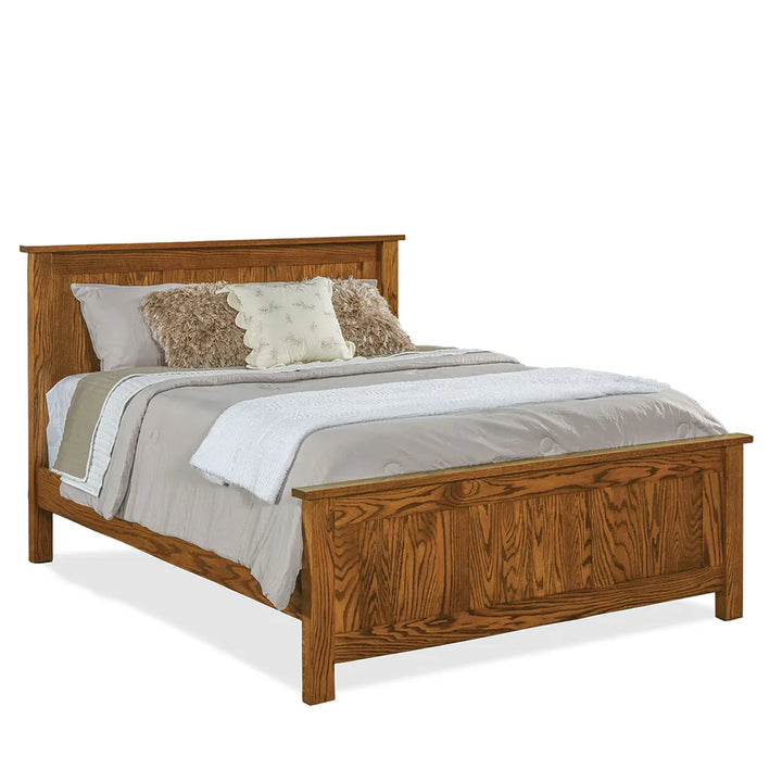 A medium brown wooden bed frame with a headboard and footboard, styled with gray bedding, white sheets, and decorative pillows, shown on a white background.