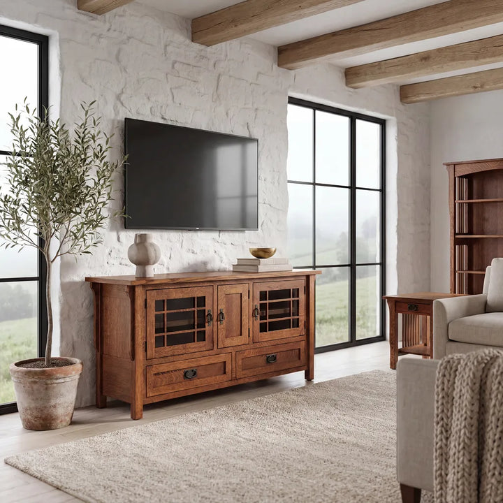 A rustic wooden TV stand cabinet with glass-paneled doors and drawers, styled in a bright, modern farmhouse living room with a mounted flat-screen TV, a potted olive tree, and a large window.