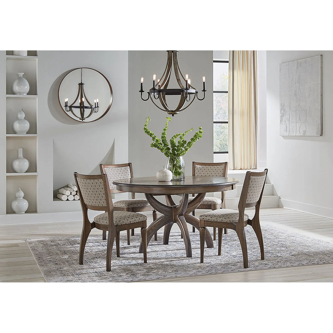 A 5-piece dining set featuring a round dark wood table and four matching armchairs with woven beige upholstery, styled in a bright, modern dining room.