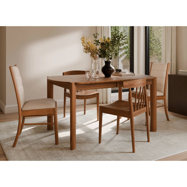 A 5-piece wooden dining table set with four chairs featuring cream upholstered seats, styled in a bright, modern dining room with a neutral rug and window backdrop.