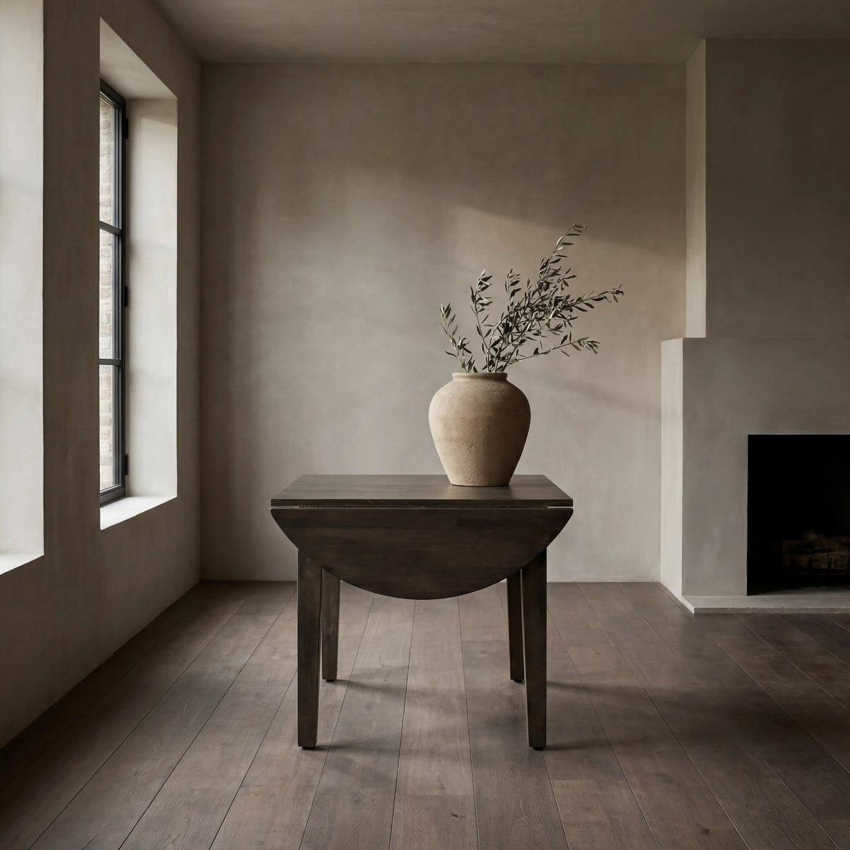 Vase with branches on a wooden table in a minimalistic room with a fireplace.