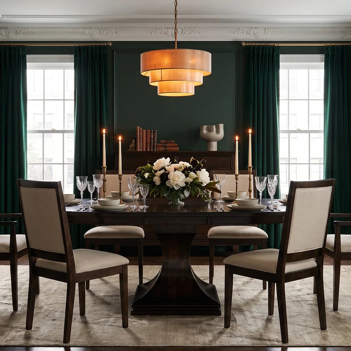 Amish Tables Westin Pedestal Dining Table in a dark wood finish, paired with Wescott upholstered chairs in an elegant dining room with deep green walls, candles, and floral centerpiece.