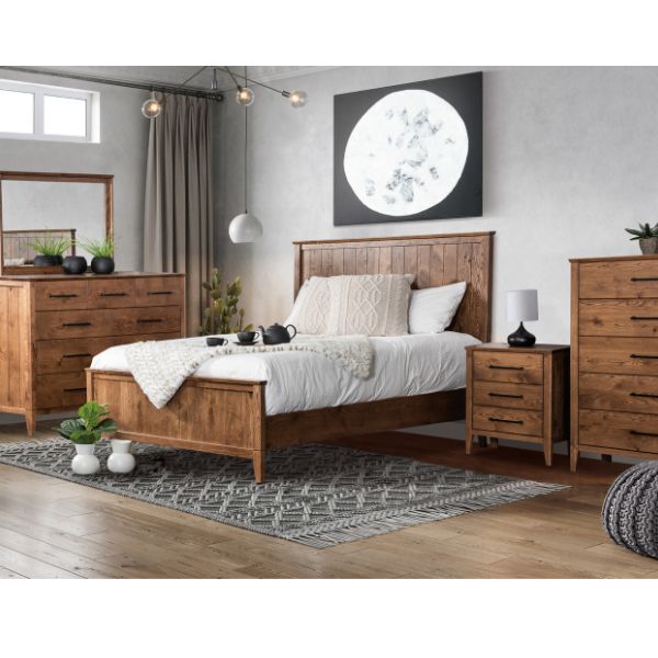 A set of brown wooden bedroom furniture, including a bed with headboard, a dresser, a nightstand, and a chest, arranged in a room with a modern farmhouse style decor.
