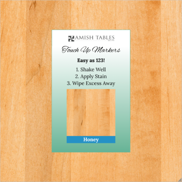 A product image featuring a 'Honey Touch Up Marker' packaging with a wooden background. The packaging is labeled with the brand 'Amish Tables' and has text instructions for use.