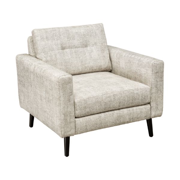 A well-lit living room featuring a beige upholstered sofa set with a design that includes mission lines, alongside a matching armchair and footstool, set on a patterned rug.