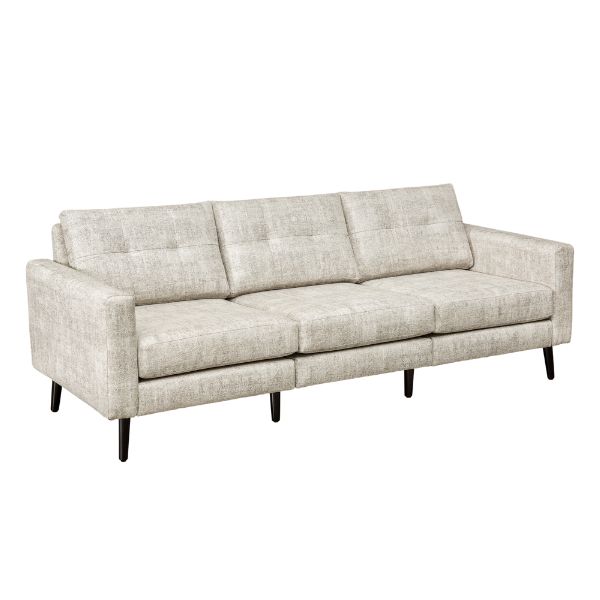 A well-lit living room featuring a beige upholstered sofa set with a design that includes mission lines, alongside a matching armchair and footstool, set on a patterned rug.