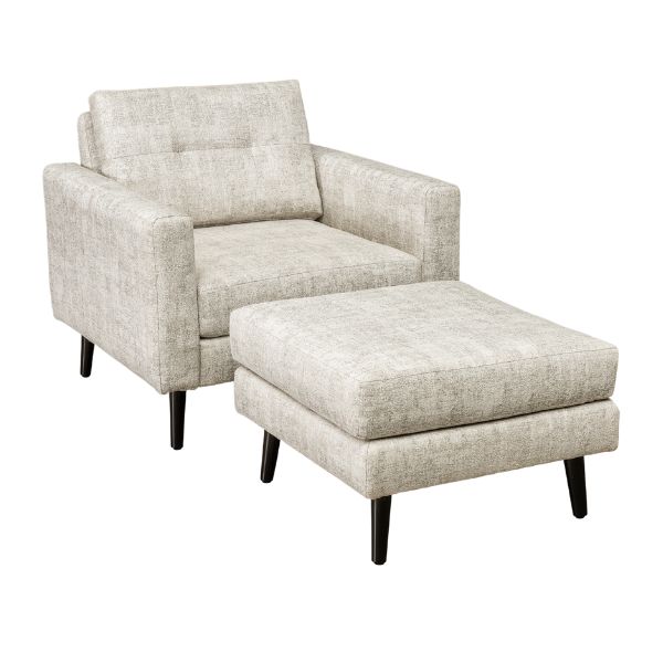 A well-lit living room featuring a beige upholstered sofa set with a design that includes mission lines, alongside a matching armchair and footstool, set on a patterned rug.